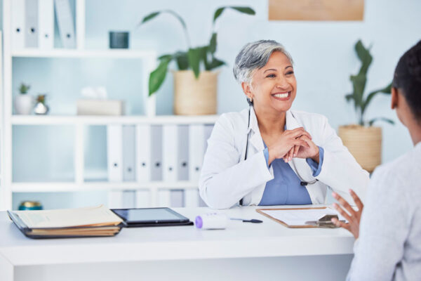 Health-care practitioner sitting at desk talking to patient